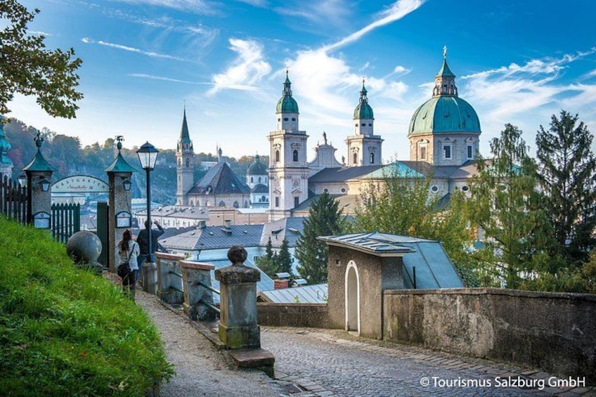Eine historische Kirche mit Kuppeldächern und Türmen, ein Kopfsteinpflasterweg und ein klarer Himmel. 5