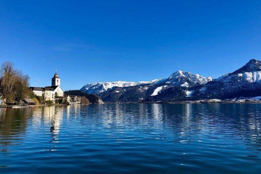 A calm lake with a church and snow-capped mountains in the background. 4