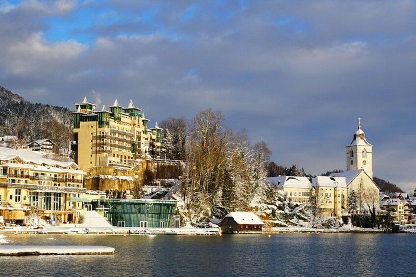 A winter town with buildings, a church, and a river. 3