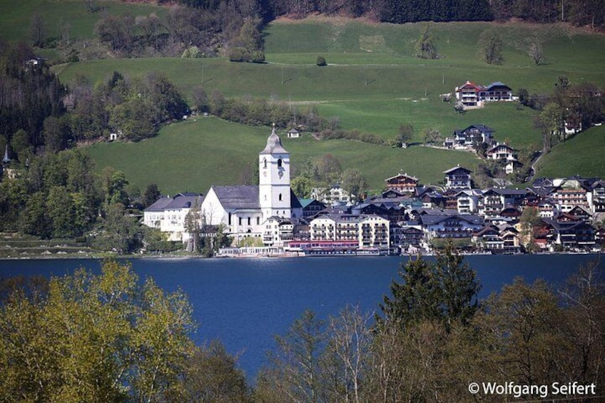 A lakeside town with a prominent church, a tower, and a cluster of buildings. 5