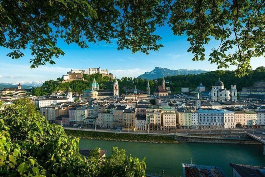 A cityscape with a river, historic buildings, and a castle on a hill. 4