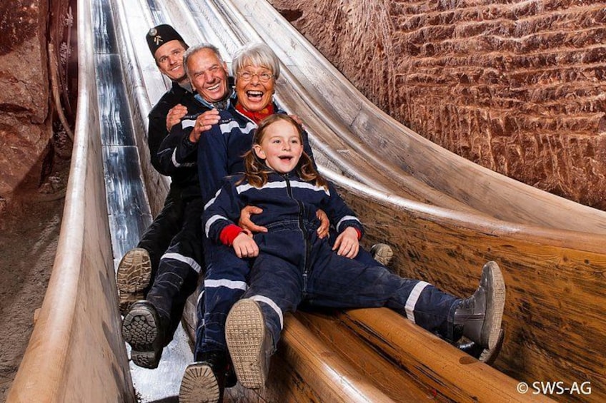 Eine Holzrutsche mit darauf sitzenden Personen. 2
