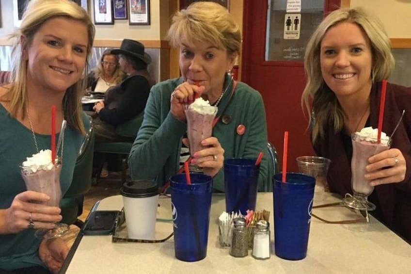 Tres personas sentadas en una mesa con tazas azules y una taza blanca, disfrutando de postres. 4