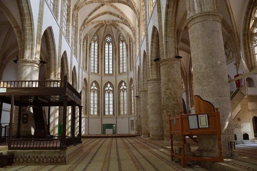 Interno di una cattedrale con soffitti a volta alta, ampie vetrate istoriate e una navata centrale. 3