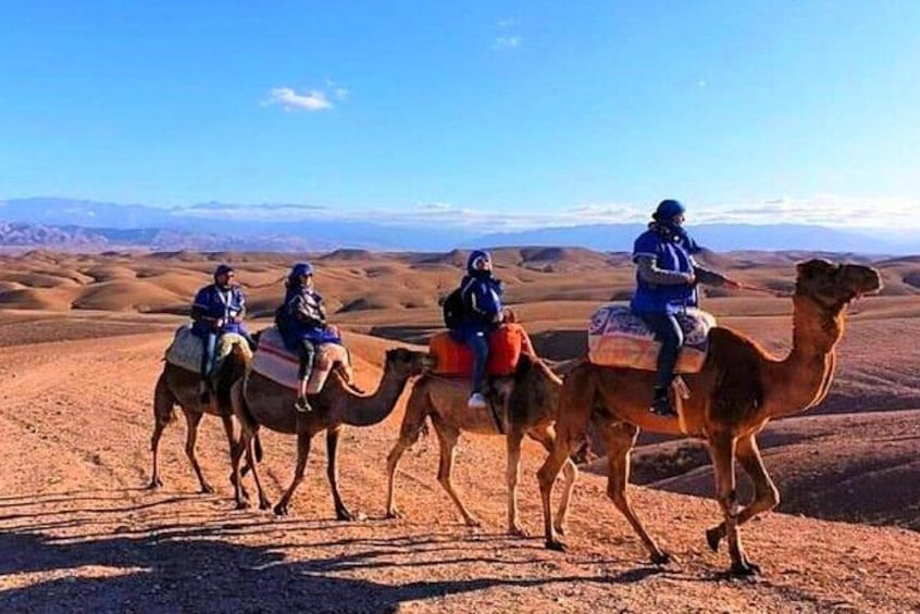 Three people riding camels in a desert landscape. 4