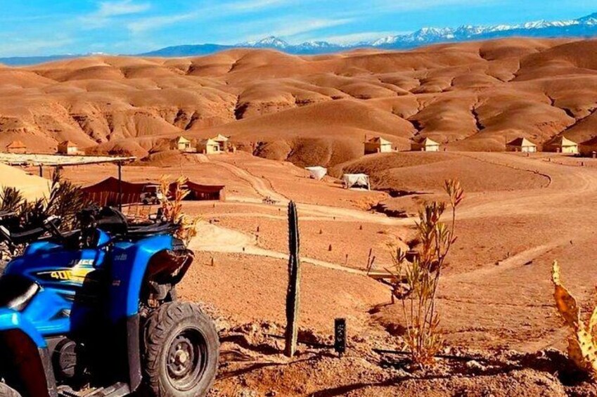 A desert landscape with rolling hills, sparse vegetation, and a blue off-road vehicle in the foreground. 2