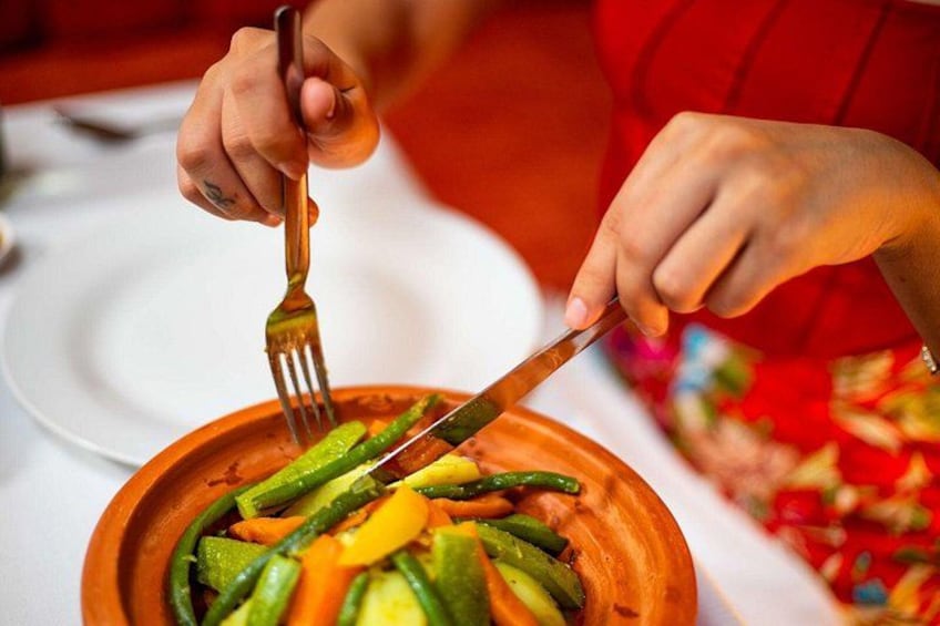 Una persona cortando verduras con un tenedor y un cuchillo en un plato. 4