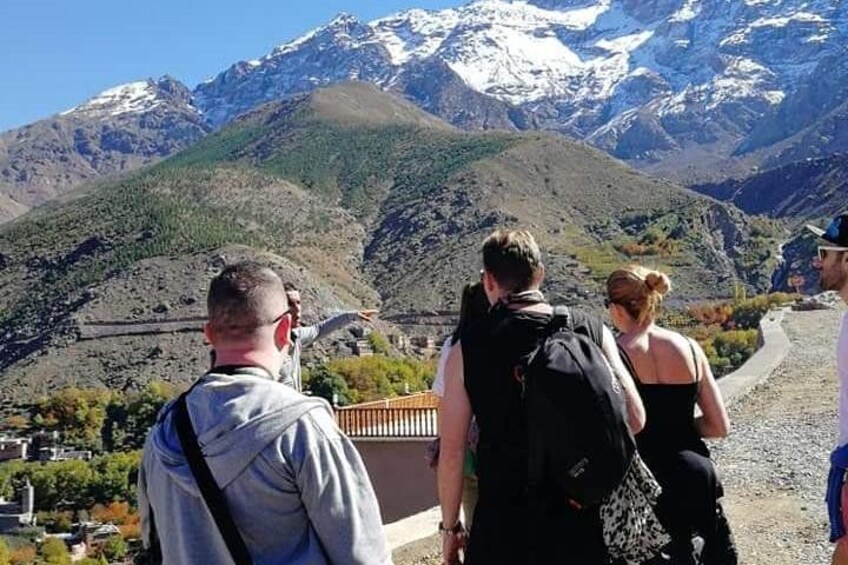 A group of hikers on a mountain trail with snow-capped peaks in the background. 2
