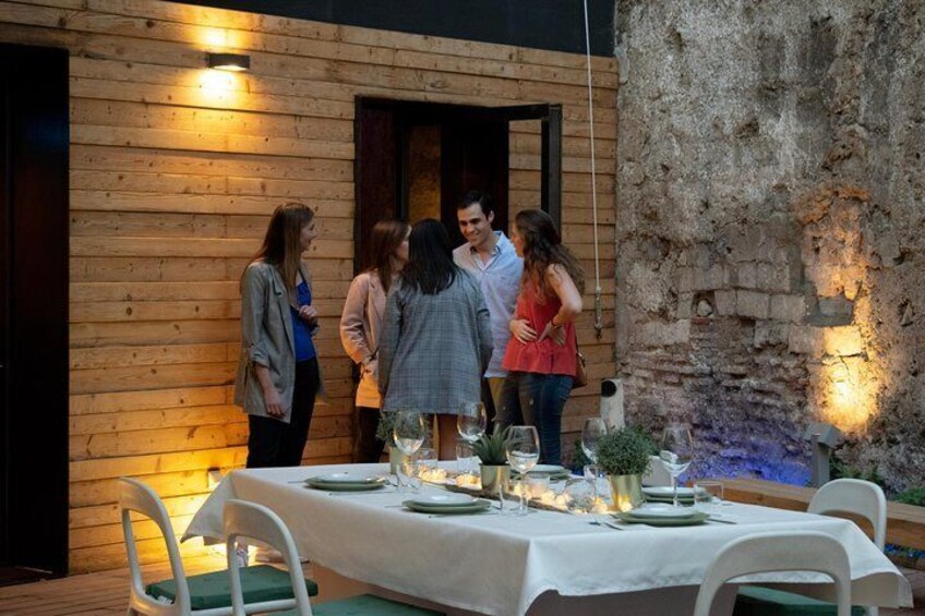 Un bâtiment en bois, avec une table dressée pour un repas, entouré de personnes. 2