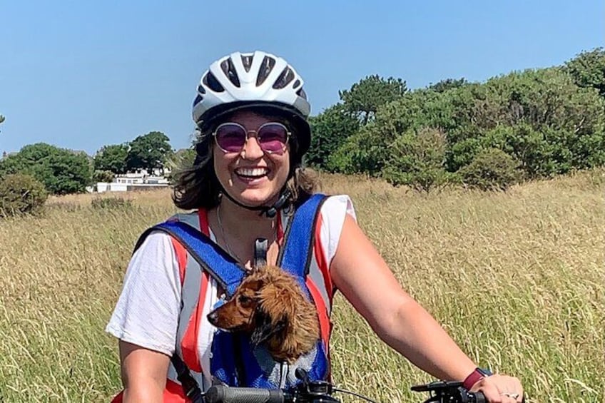 A person on a bicycle in a field with a dog. 2
