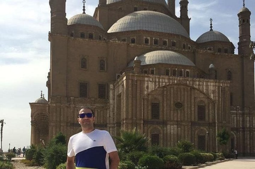 A man standing in front of a large, historic building with multiple domes and minarets. 2