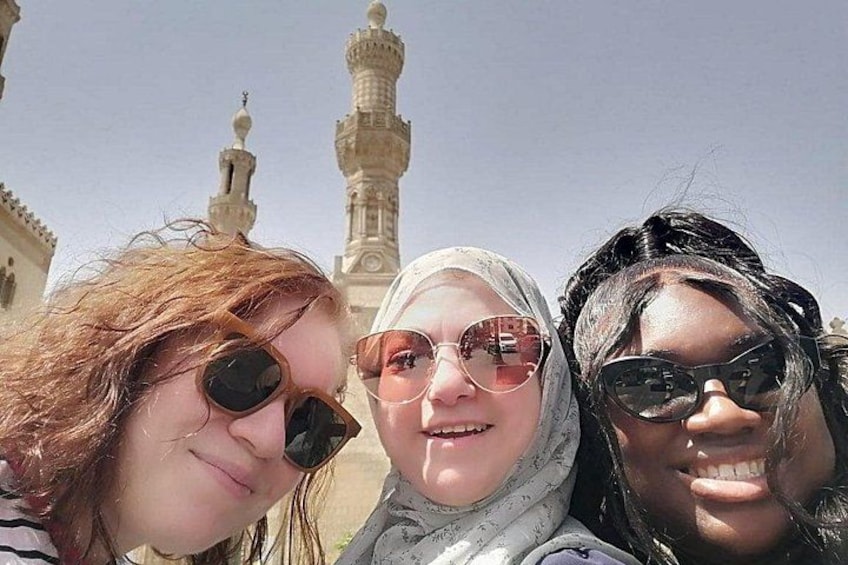 Trois personnes se tiennent devant une mosquée dont les minarets sont visibles. 2