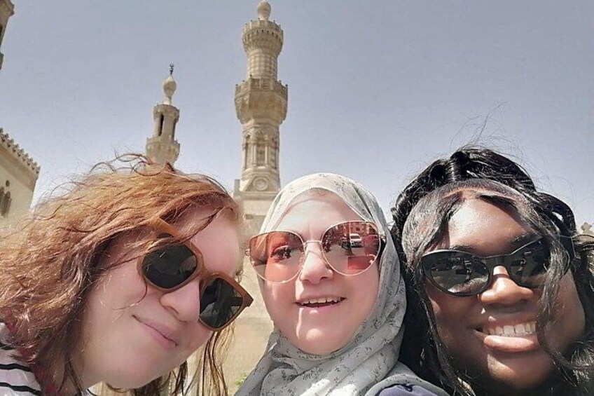 Three people in front of a mosque with a minaret. 3