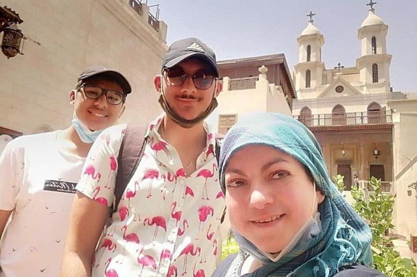 Trois personnes se tiennent devant un bâtiment surmonté d’une croix. 4