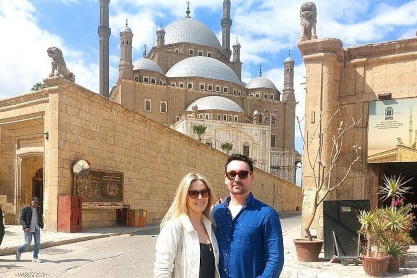 A historic building with domes and minarets, a paved street, and potted plants. 4