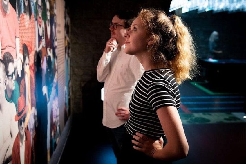 Two people standing in front of a wall with colorful murals. 3