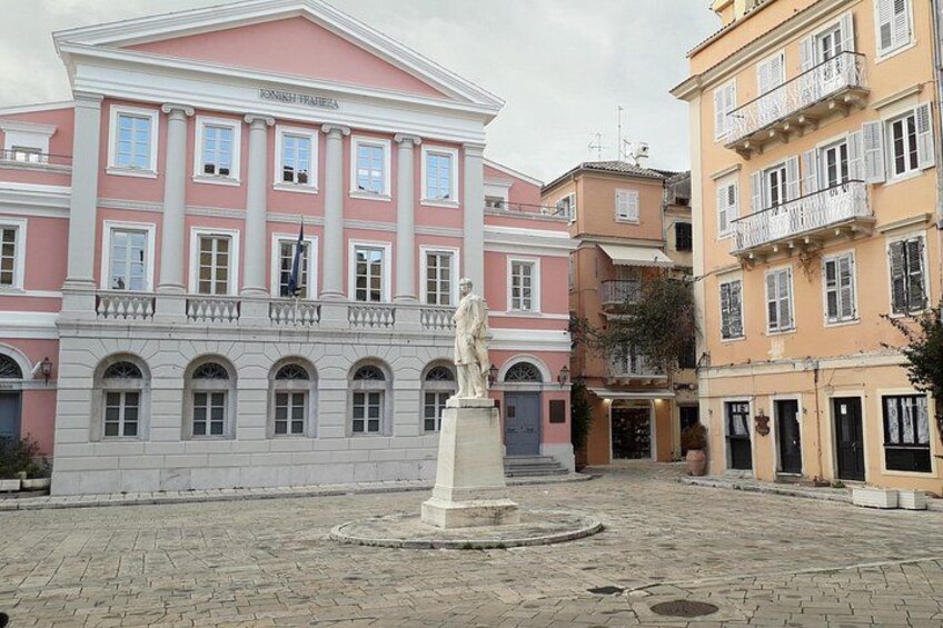 Une place avec une statue, des bâtiments roses et jaunes, et un pavé de pierres. 2