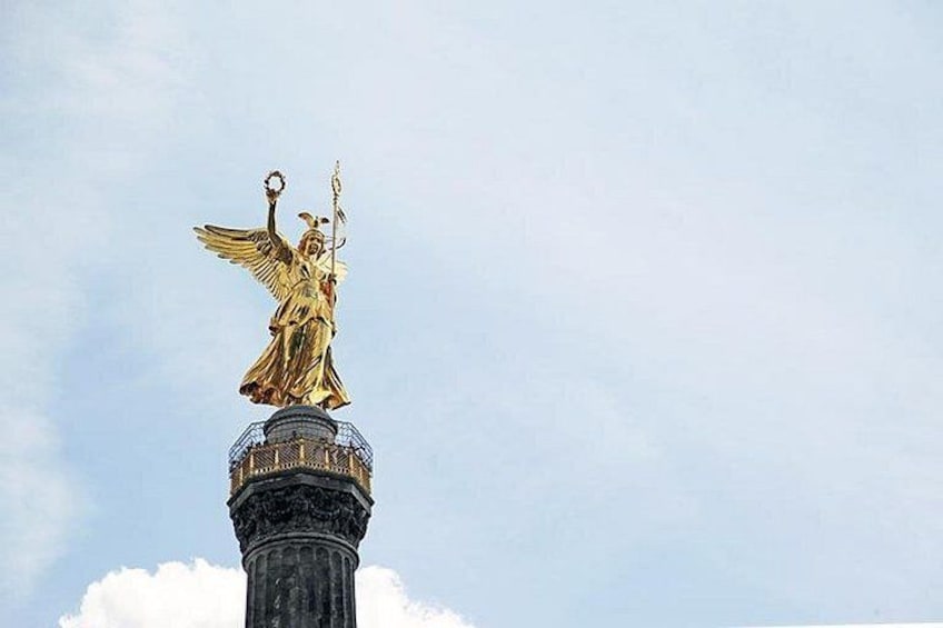 A golden statue atop a column with inscriptions. 2