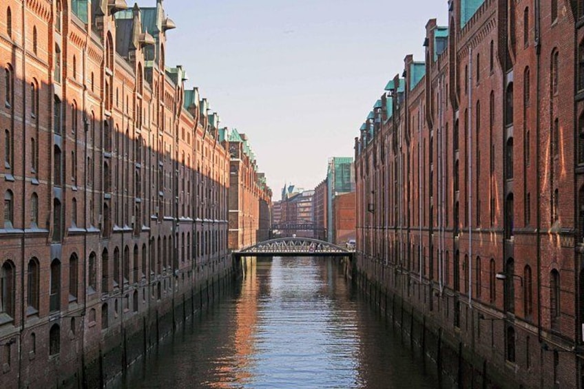 A canal flanked by brick buildings with a bridge in the distance. 2