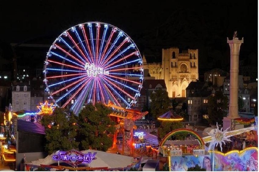 Une grande roue, un château et une statue se dressent dans un paysage urbain nocturne. 5