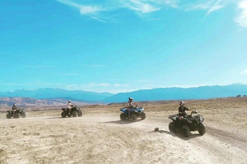 Quatre personnes conduisent des quads sur un chemin de terre, avec un paysage montagneux en arrière-plan. 5