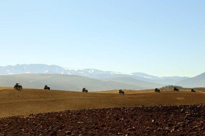 Un groupe de véhicules tout-terrain sur un paysage désolé, avec des montagnes qui se dessinent à l’horizon. 3
