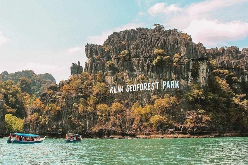 A boat on water with a cliff and trees labeled 'Kilim GeoForest Park.' 1