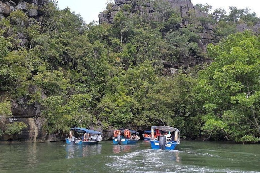 Three boats on a river with dense greenery and rocky cliffs in the background. 5