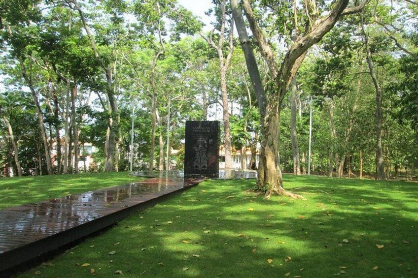 A park with a reflective water feature, a large tree, and a stone structure. 3