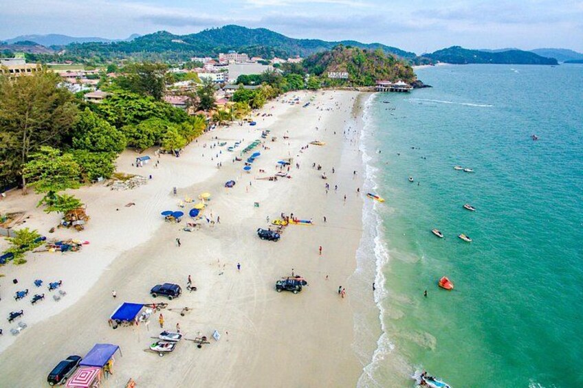 A beach with people, umbrellas, and boats. 1