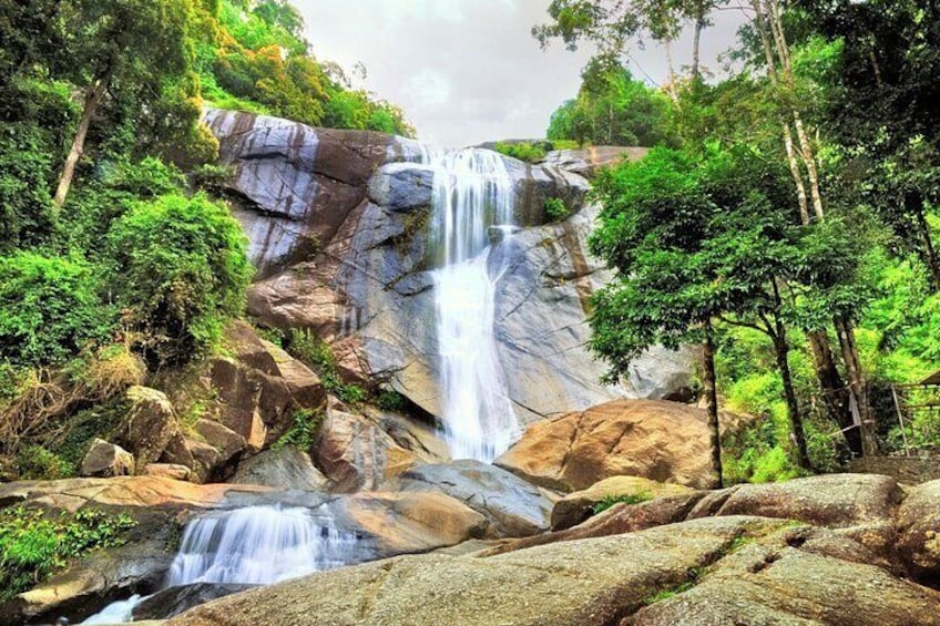 A waterfall cascading over rocky terrain surrounded by lush greenery. 1