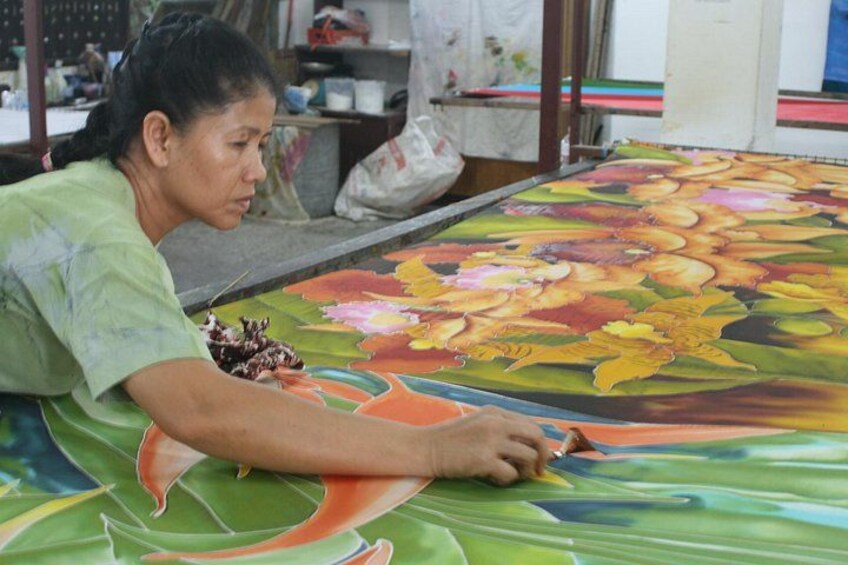 A person working on a large, colorful fabric with floral patterns. 4