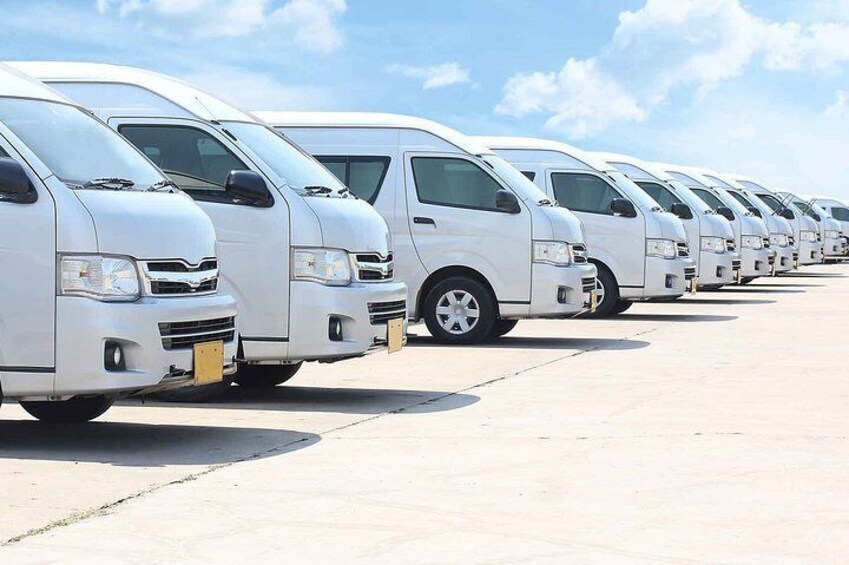 A row of white vans parked in a lot. 3
