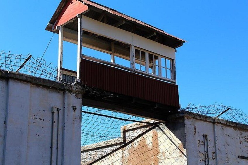 A watchtower with a red roof, barbed wire, and a metal fence. 2