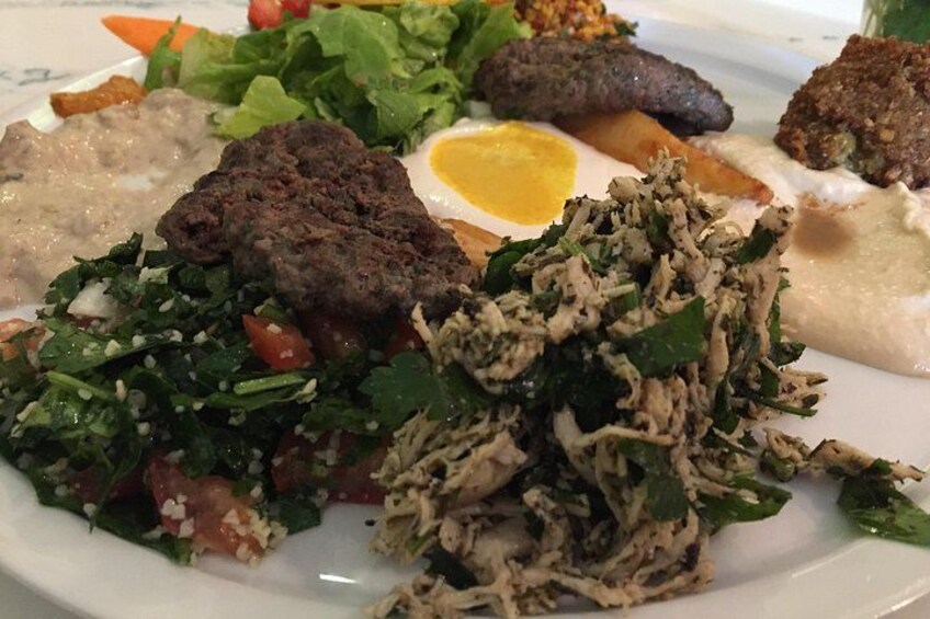 Ein Teller mit verschiedenen Speisen, darunter Salat, Fleisch und ein Spiegelei. 2