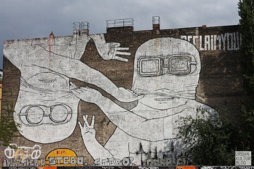 Une fresque murale sur un mur de briques représentant deux personnages, l’un portant des lunettes et l’autre des lunettes de protection, et sur laquelle on peut lire le mot « DÉCLINANT ». 5