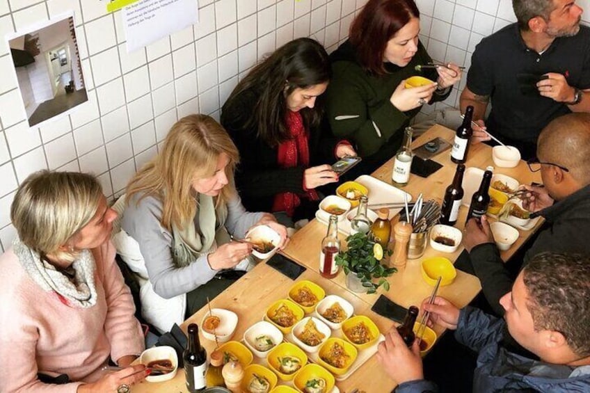 Un groupe de personnes est réuni autour d’une table, où se trouvent divers plats et boissons. 4