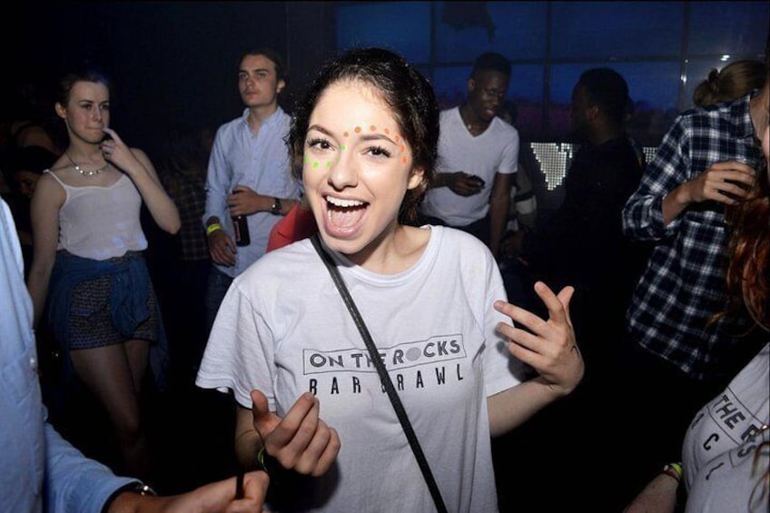 Une personne portant un t-shirt blanc avec une inscription, debout dans un lieu intérieur bondé. 3