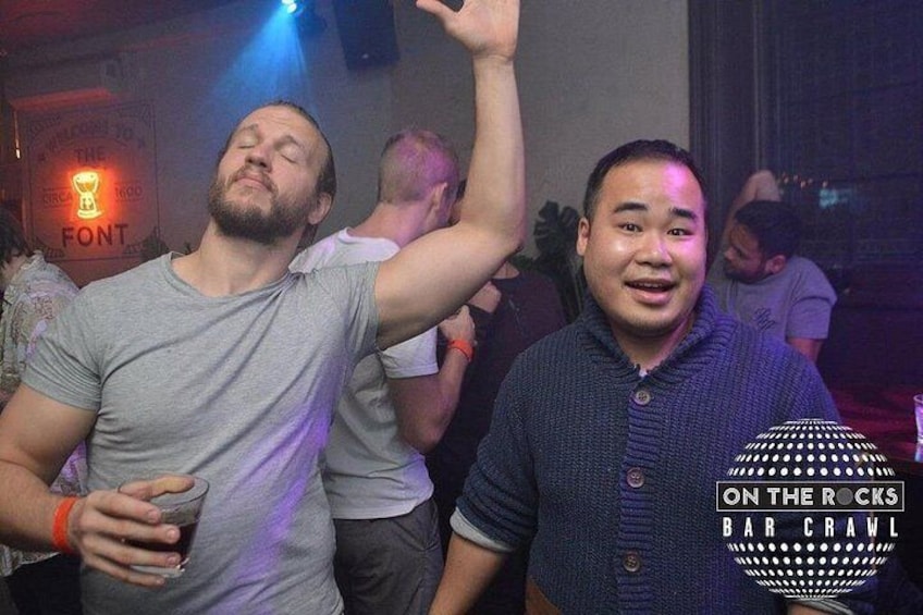 Deux personnes sont assises au bar, et une pancarte indique : « ON THE ROCKS BAR CRAWL ». 5