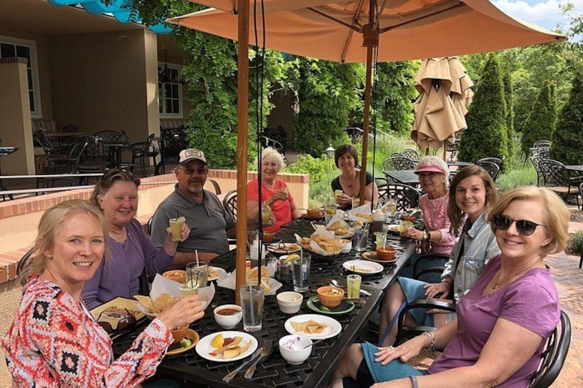 A group of people dining outdoors at a table with food and drinks. 5