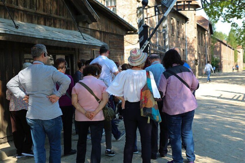 A group of people standing in front of a wooden building, possibly a historical site. 5
