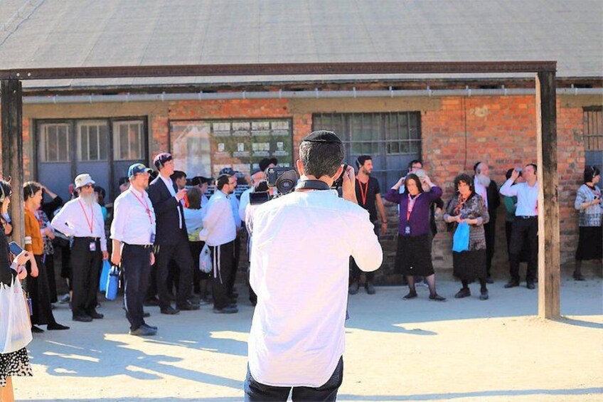 A group of people standing in a line outside a building with a brick facade. 4