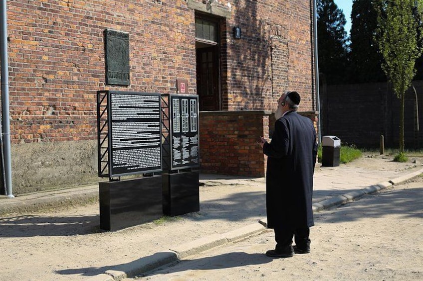 A man standing next to a black metal information board on a street. 5