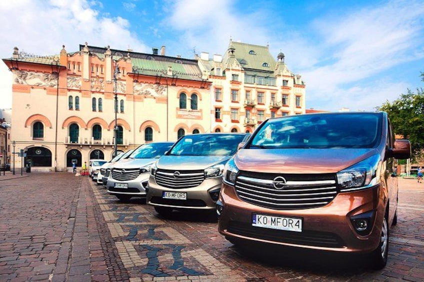 A row of parked cars in front of a historic building with arched windows and a tiled roof. 3
