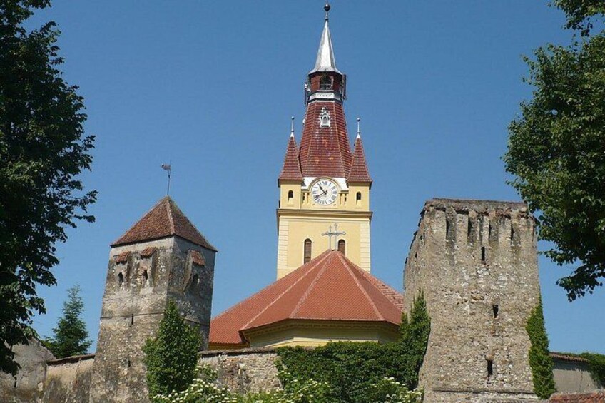 A historic building with a clock tower, a red-roofed central structure, and two stone towers. 5