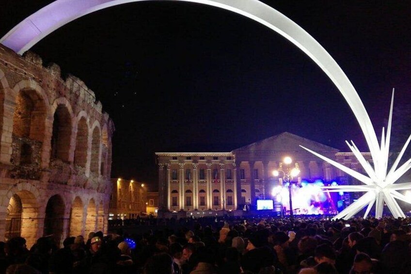 A crowd at a public event with a classical building and a modern sculpture in the background. 5