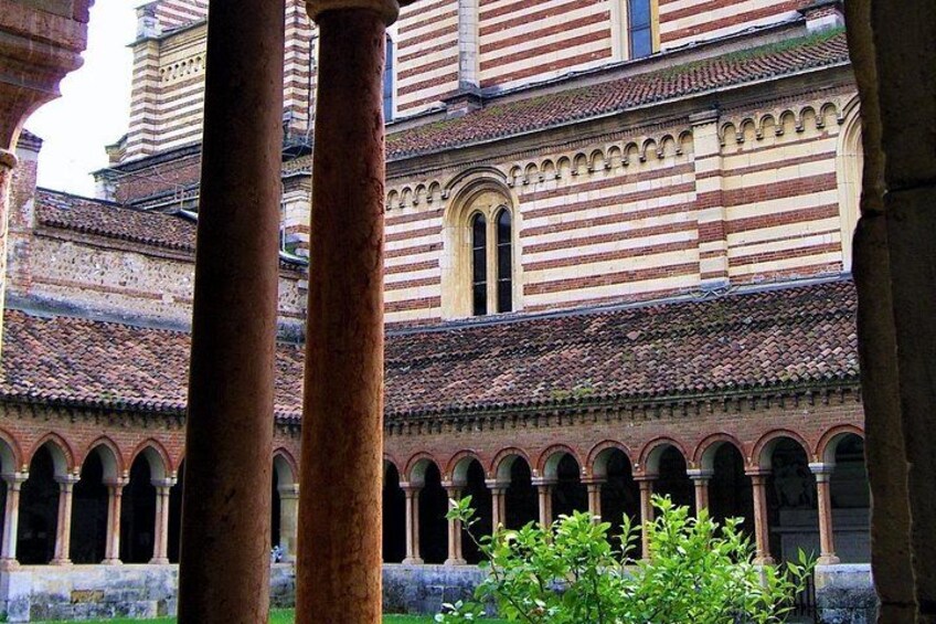 A historic building with striped brickwork, arched windows, and columns. 2
