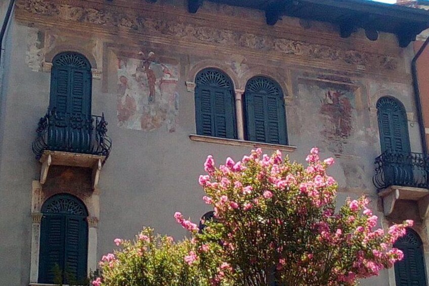 A building with arched windows and balconies, and a flowering tree in the foreground. 3