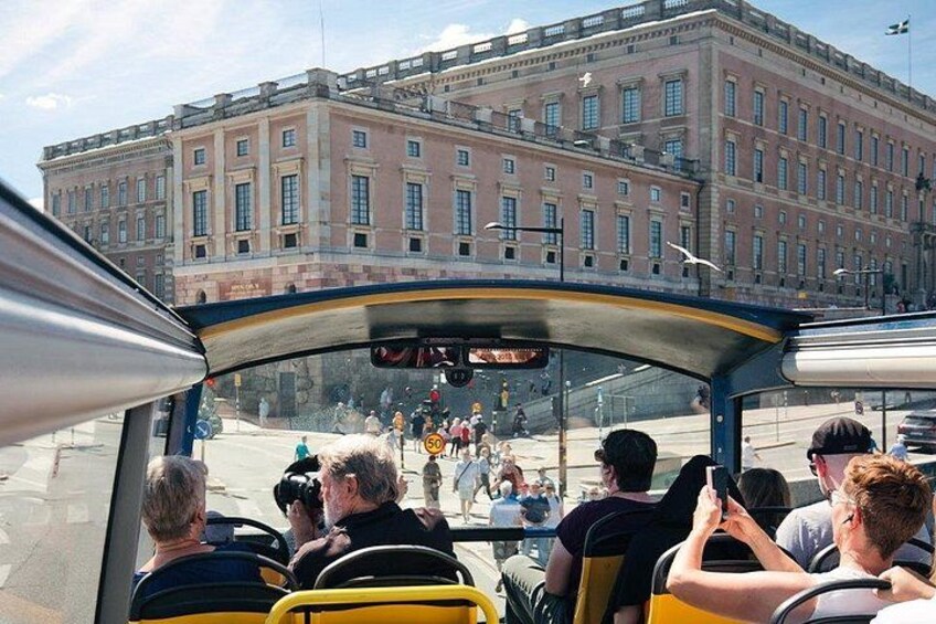 A bus with passengers, a building in the background, and a street scene. 5
