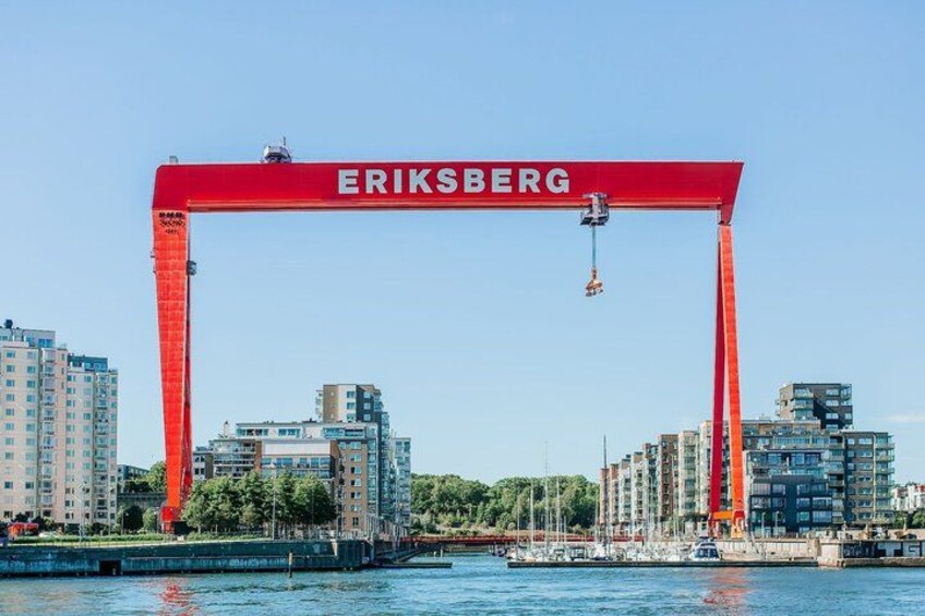 A red arch with 'ERIKSBERG' written on it, spanning over a body of water with buildings and a bridge in the background. 4